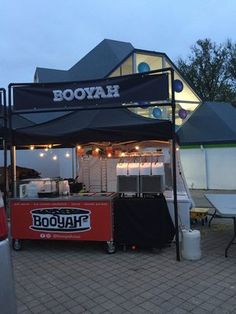 a booth set up for an outdoor event with lights on the roof and tables under it