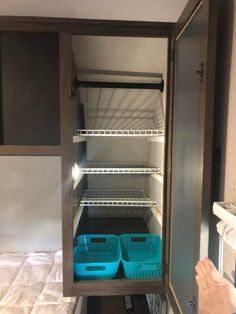 an empty pantry with two blue plastic baskets in the bottom shelf and one green basket on the bottom shelf