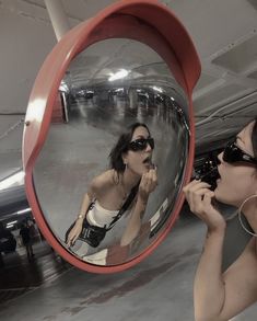 a woman is brushing her teeth in front of a mirror with an airplane behind her