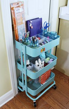 a blue cart filled with lots of items on top of a hard wood floor