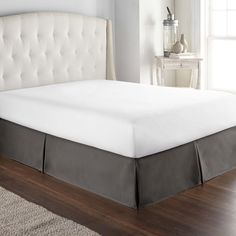 a bed with a white headboard and beige bedskirt