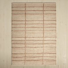 a beige rug with vertical lines on the bottom and one line at the top, in front of a white wall