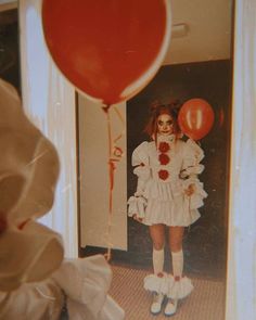 a woman dressed in white holding a red balloon