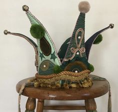 a wooden chair with two green hats on it's legs and one sitting on top of the chair