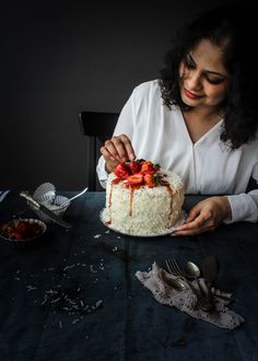 a woman sitting at a table with a cake in front of her