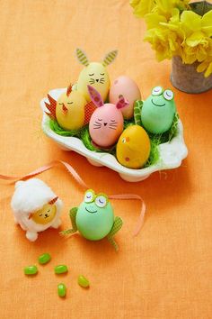 an arrangement of easter eggs in a bowl on a table with flowers and other decorations