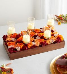 an arrangement of flowers and candles on a table