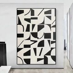 an abstract black and white painting hangs on the wall