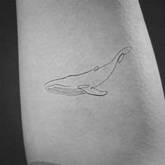 a black and white photo of a small whale tattoo on the right side of the leg