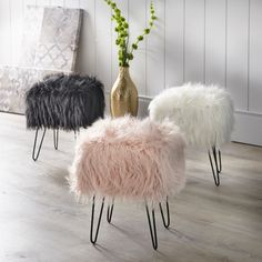 three sheepskin stools with hairpink legs in front of a white wall