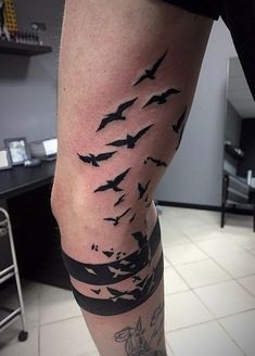 a man's leg with birds flying in the sky on his left calf tattoo