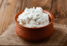 a bowl filled with whipped cream on top of a wooden table next to a spoon