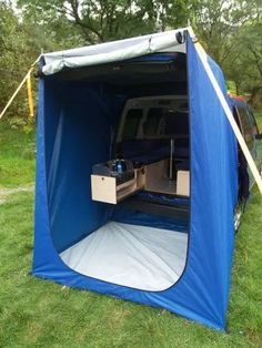 an open blue tent sitting on top of a lush green field