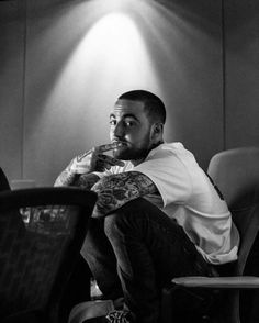 a black and white photo of a man sitting in a chair with his arms crossed