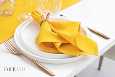 a white plate topped with yellow napkins on top of a table