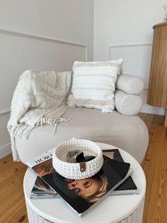 a white table topped with magazines and a magazine on top of it next to a couch