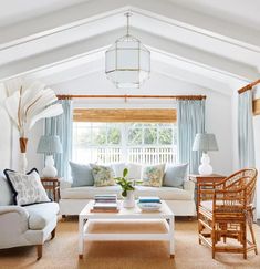 a living room with white furniture and blue curtains