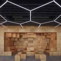 an empty room with wooden benches and lights hanging from the ceiling over it's walls