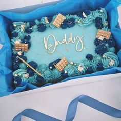 a birthday cake in a box with the word daddy written on it and blue icing