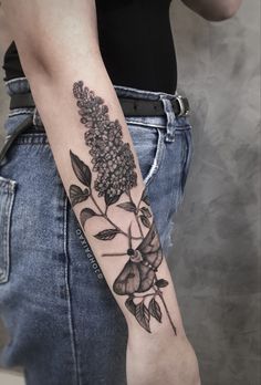 a woman's arm with flowers on it and leaves in the middle of her arm