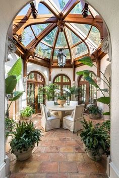 an indoor dining area with potted plants in the center and large glass doors leading to another room