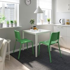 two blue chairs sitting at a white table with a clock on the wall above it