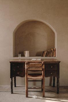 an old desk with a book shelf in the corner and a coffee cup on it