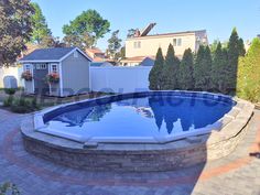 a backyard with a swimming pool surrounded by landscaping