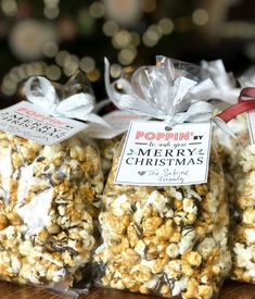 three bags of popcorn sitting on top of a wooden table next to a christmas tree