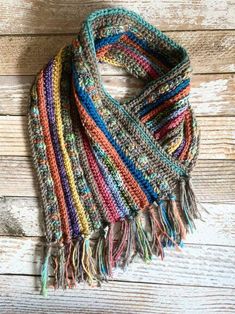 a multicolored knitted scarf hanging on a wooden wall with wood planks in the background