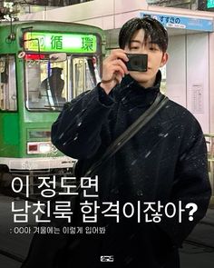 a man taking a photo with his cell phone in front of a bus on the street