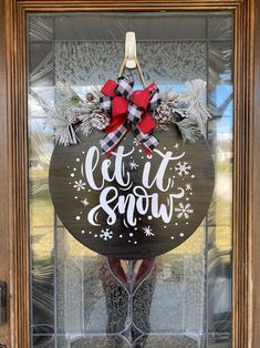 a christmas door hanger with the words let it snow written in white letters and red bows