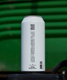 a can of soda sitting on top of a black table next to a green wall