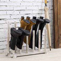 several pairs of boots are lined up on a rack in front of a brick wall