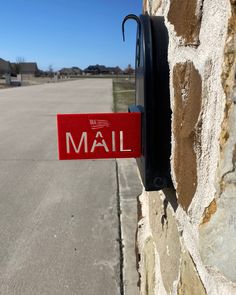 a mailbox mounted to the side of a stone wall with a red sign that says mail