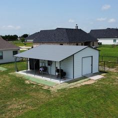 a small white building sitting on top of a lush green field next to two buildings