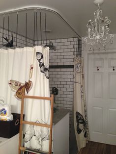 a bathroom with a shower curtain, rugs and a ladder in front of it