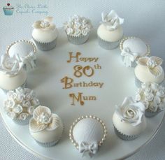 a birthday cake decorated with cupcakes and white frosting on a plate that says happy 80th birthday mum