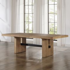 a large wooden table sitting on top of a hard wood floor next to two windows