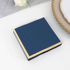 a blue book sitting on top of a white table next to a plate and flowers