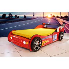 a red and yellow car shaped bed sitting on top of a white tile floor next to a highway