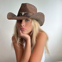 a woman wearing a cowboy hat with her hand on her chin looking at the camera