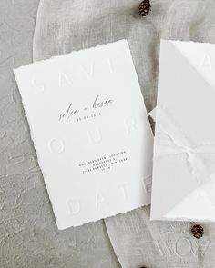 the wedding stationery is laid out with pine cones