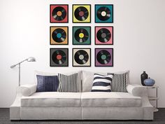 a white couch sitting in front of a wall filled with different types of vinyl records