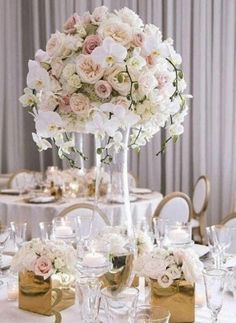 a vase filled with white and pink flowers on top of a table covered in candles