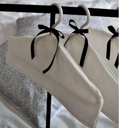 two pairs of white socks hang from a black iron bed rail with decorative bows on them