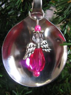 an ornament hanging from a christmas tree with pink beads and angel wings on it