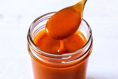 a spoon full of sauce sitting on top of a jar