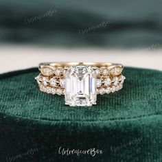 an emerald colored diamond ring on top of a green velvet box with diamonds around it