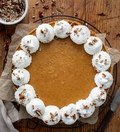 a pumpkin pie with whipped cream and pecans on the top is ready to be eaten